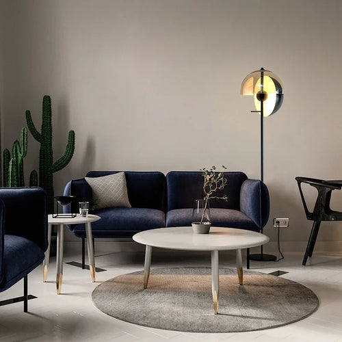 Modern living room with a blue sofa, round coffee table, and decorative elements.
