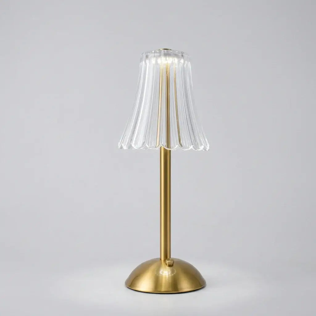 Hero - Cordless Table lamp with a clear glass shade and gold base on a dark background