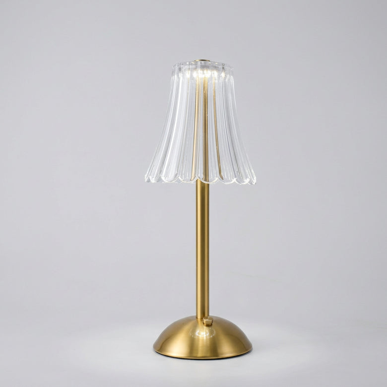 Hero - Cordless Table lamp with a clear glass shade and gold base on a dark background