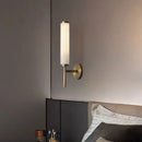 Stylish Art Deco Brass Wall Lamp illuminating a modern bedroom with a frosted glass shade and brass finish.