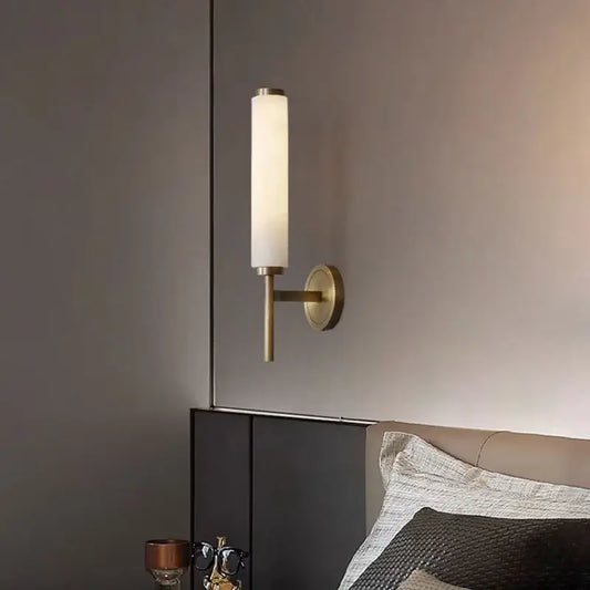 Stylish Art Deco Brass Wall Lamp illuminating a modern bedroom with a frosted glass shade and brass finish.