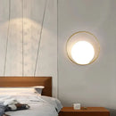 Modern Simple Art Deco Revival Wall Lamp illuminating a stylish bedroom interior with a golden circular frame.