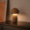 Portable Dimmable 60s Italy Designer Mushroom Table Lamp on a wooden surface, emitting a warm glow in a cozy setting.