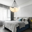 Contemporary Frosted Glass Ball & Gold Chain Chandelier illuminating a modern bedroom with elegant decor.