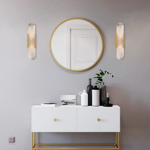 Modern interior featuring Posh Marble & Gold Roman Villa Sconce, round mirror, and stylish white cabinet.
