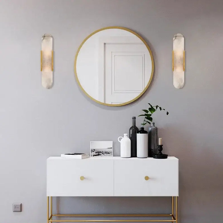 Modern interior featuring Posh Marble & Gold Roman Villa Sconce, round mirror, and stylish white cabinet.