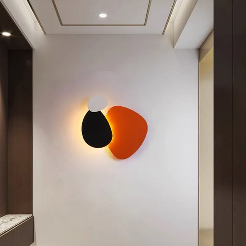Modern wall lamp with black and orange design on a white wall.
