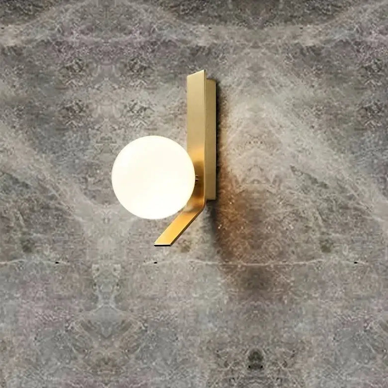 Contemporary Golden Wall Lamp with Glass Ball mounted on textured wall