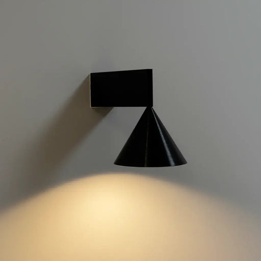 Hero Black wall-mounted light fixture casting a warm glow on a gray wall.