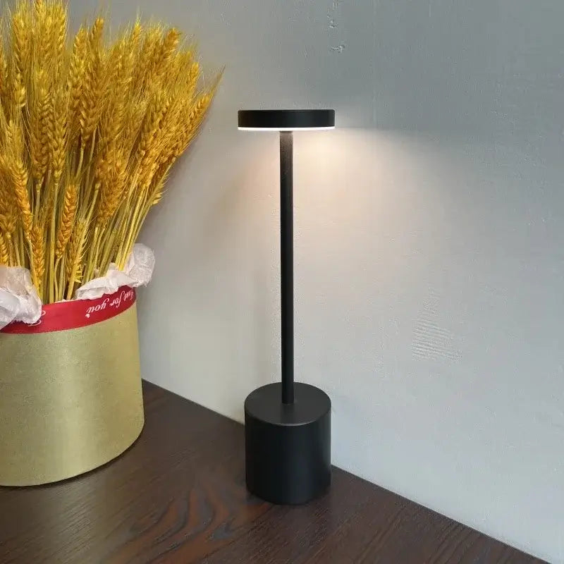 Black floor lamp on a wooden floor next to a container of wheat.