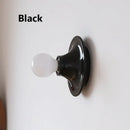 80s revival wall light in black with UFO shape and white bulb, perfect for retro decor.