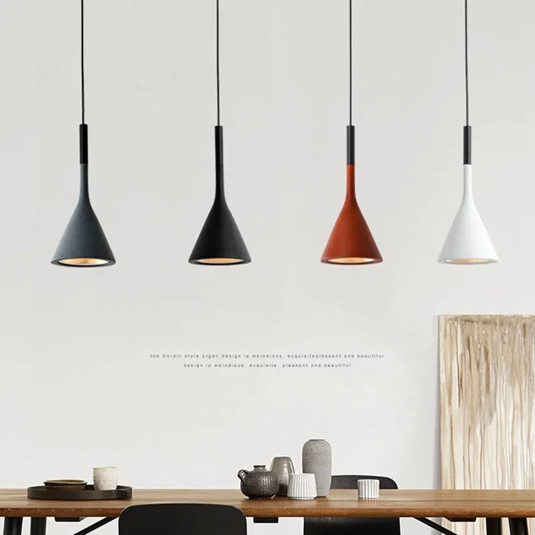 Four pendant lights in different colors hanging above a dining table with decor items.
