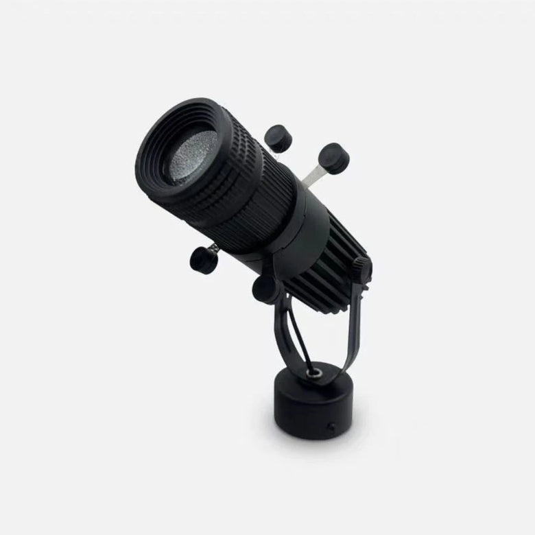 A black adjustable spotlight or searchlight with a ribbed cylindrical body, mounting bracket, and round base, photographed on a clean light gray background.