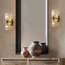 Radiant Luxe Gold Wall Sconce illuminating a stylish interior with decorative vases and a modern mirror.