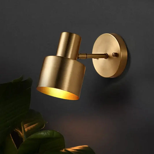 Gold Wall Mounted Spot in Brass and Black Colours illuminating a dark wall with a modern design.