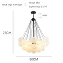 Contemporary Frosted Glass Ball & Gold Chain Chandelier with soft white lights and black fixture.