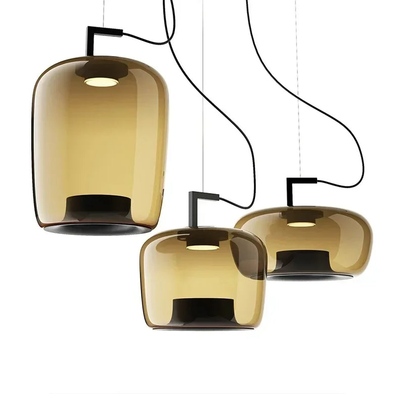 Three modern pendant lights with translucent amber-tinted glass shades and black suspension hardware, shown against a plain white background.