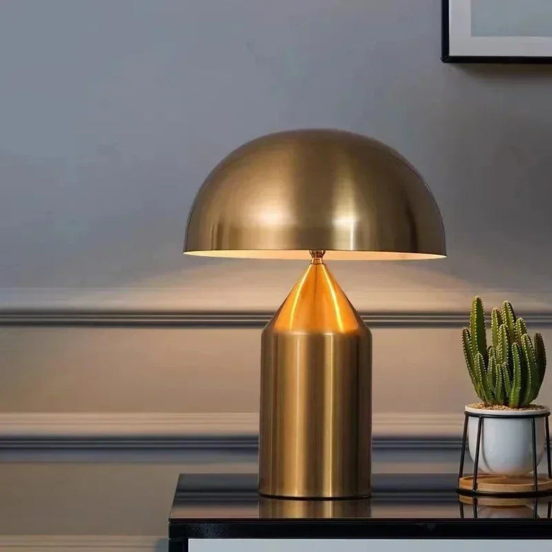 Hero Gold Mushroom able lamp on a dark surface with a cactus plant in the background