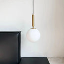 Modern Gold Glass Ball Pendant hanging above a black sofa, adding elegance to contemporary interior decor.