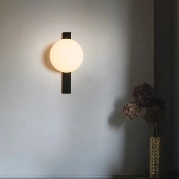 Decorative Lighting Fixture With Milk White Glass Sphere mounted on a wall, casting a warm glow in a stylish interior.