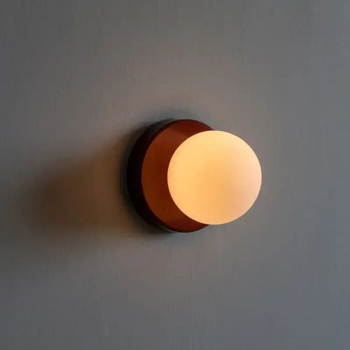 Colourful macaron wall lamp with soft glowing orb, mounted on a wall, creating a warm and inviting atmosphere.