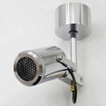 A polished chrome wall-mounted spotlight with a cylindrical head, front grille, adjustable arm, and visible black cable, shown against a plain light background.